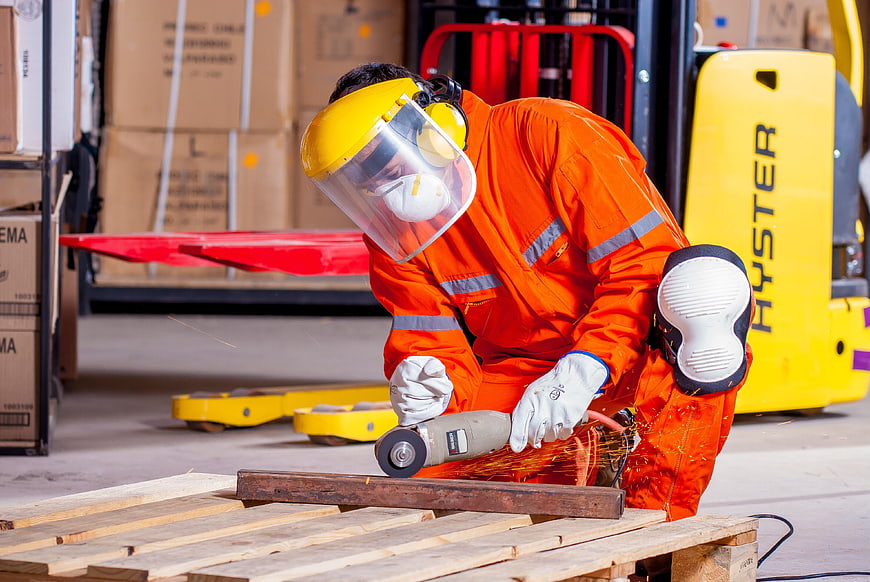 Warehouse worker grinding metal with angle grinder