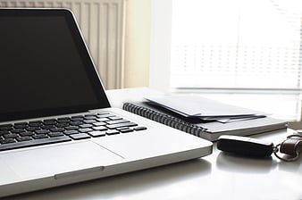Modern workspace with laptop, notebook, and car keys on desk