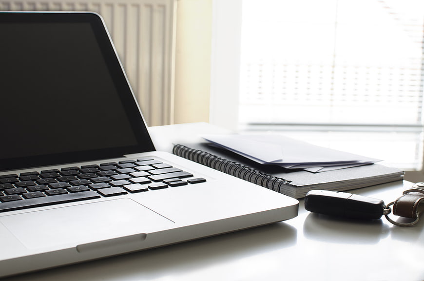 Modern workspace with laptop, notebook, and car keys on desk