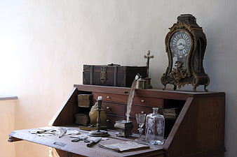 Antique wooden secretary desk with vintage clock and writing tools
