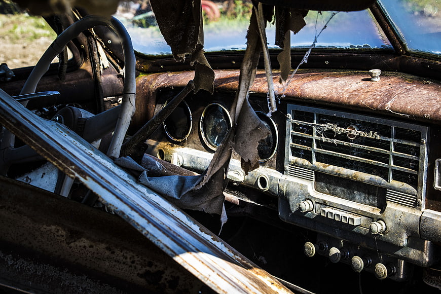 Rusty vintage Plymouth car interior with torn upholstery