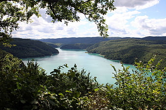 Panoramic View of Turquoise Lake Surrounded by Green Hills