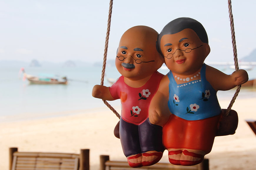 Colorful figurines of elderly couple on beach swing
