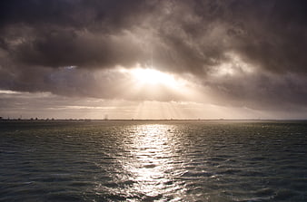 Dramatic Sun Rays Breaking Through Storm Clouds Over Ocean