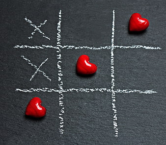 Red hearts winning tic-tac-toe game on slate background