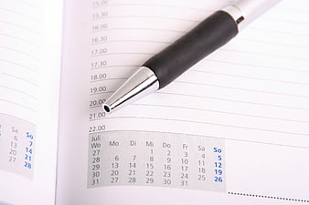Black pen on open planner with July calendar and time slots