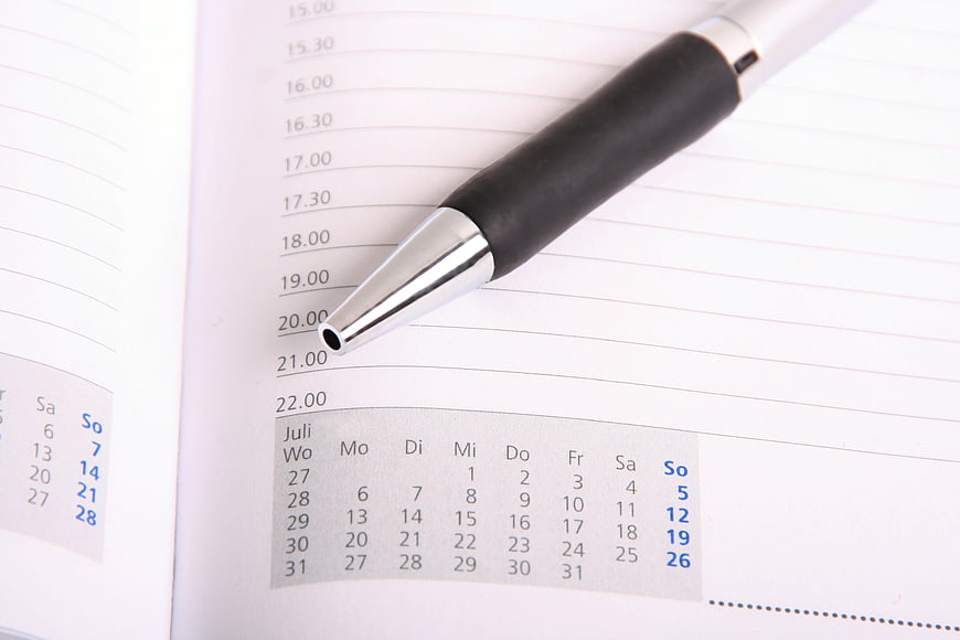Black pen on open planner with July calendar and time slots