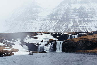 Snowy Waterfall Cascading into Lake with Mountain Background