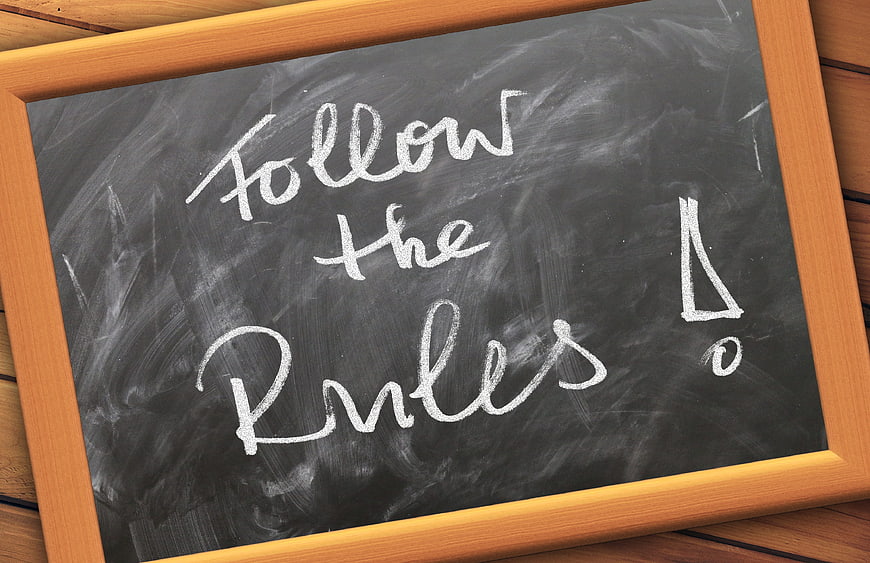 Chalkboard with handwritten text Follow the Rules on wooden table