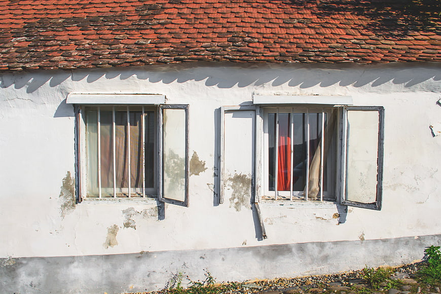 Old White House with Weathered Windows and Red Roof