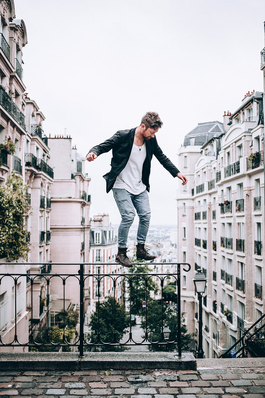 Man balancing on railing in Parisian urban street