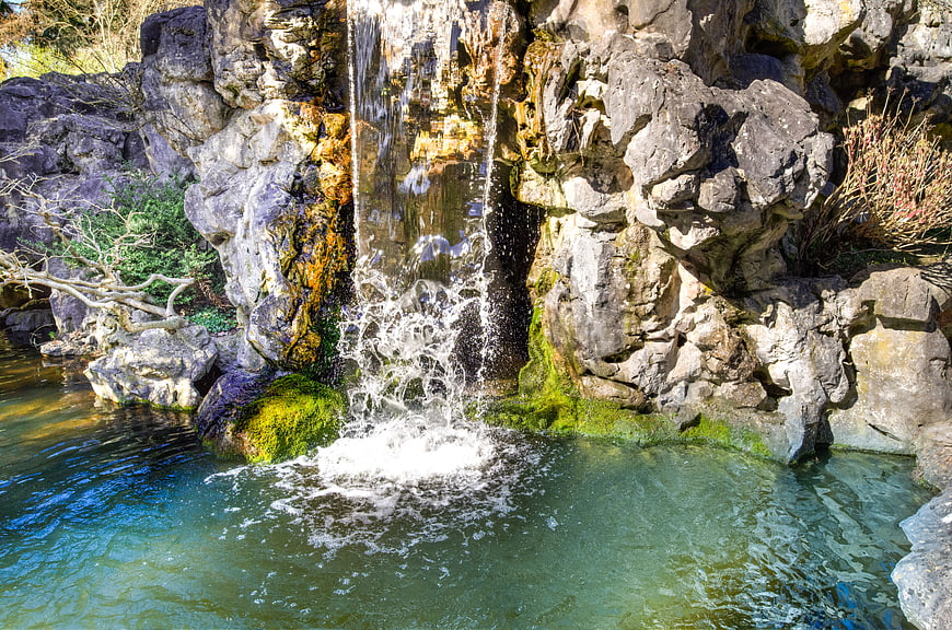 Small waterfall cascading into a clear pond surrounded by rocks