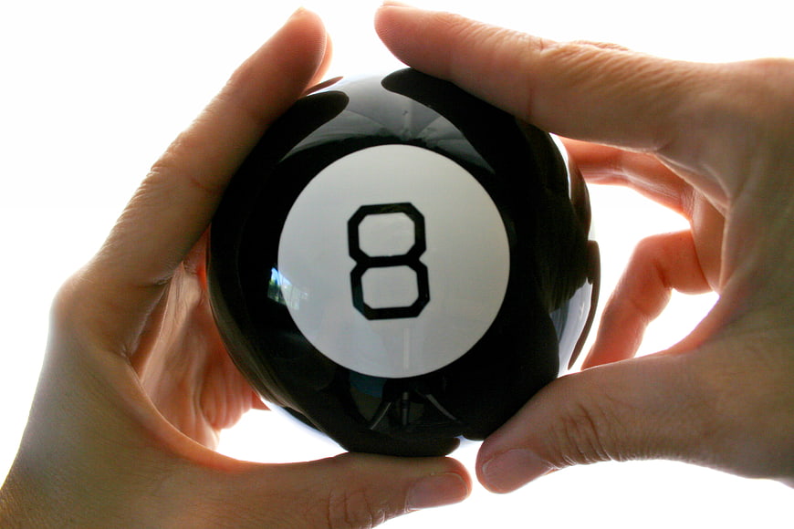 Hands holding black eight ball against white background