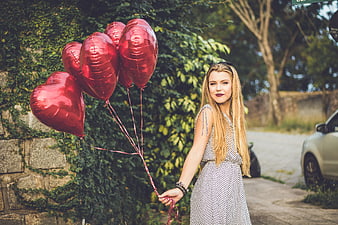 Blonde Woman Holding Red Heart Balloons Outdoors