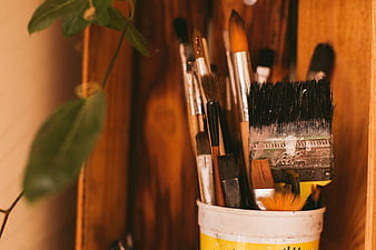 Collection of used paint brushes in a yellow cup