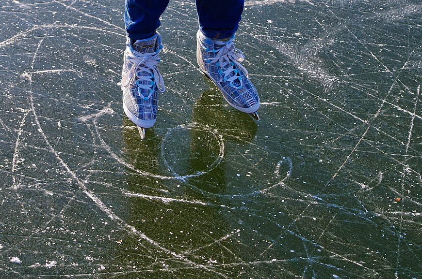 Close-up of ice skates on a scratched frozen rink surface