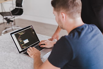 Man coding on laptop in modern office workspace