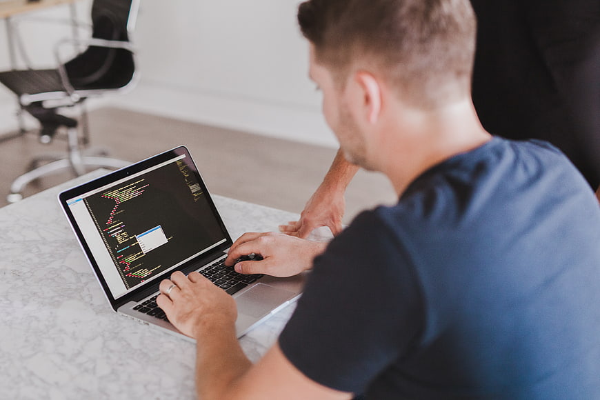 Man coding on laptop in modern office workspace
