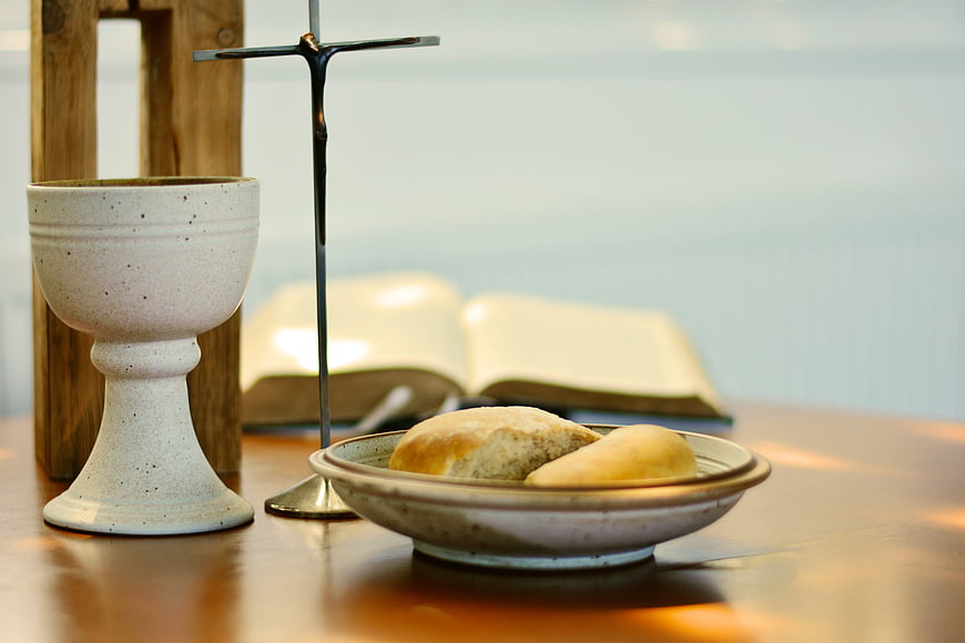 Christian communion elements with bread, chalice, cross, and bible