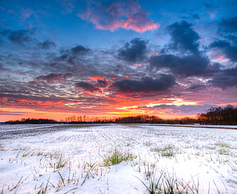 Dramatic Winter Sunset Over Snowy Field with Vibrant Clouds