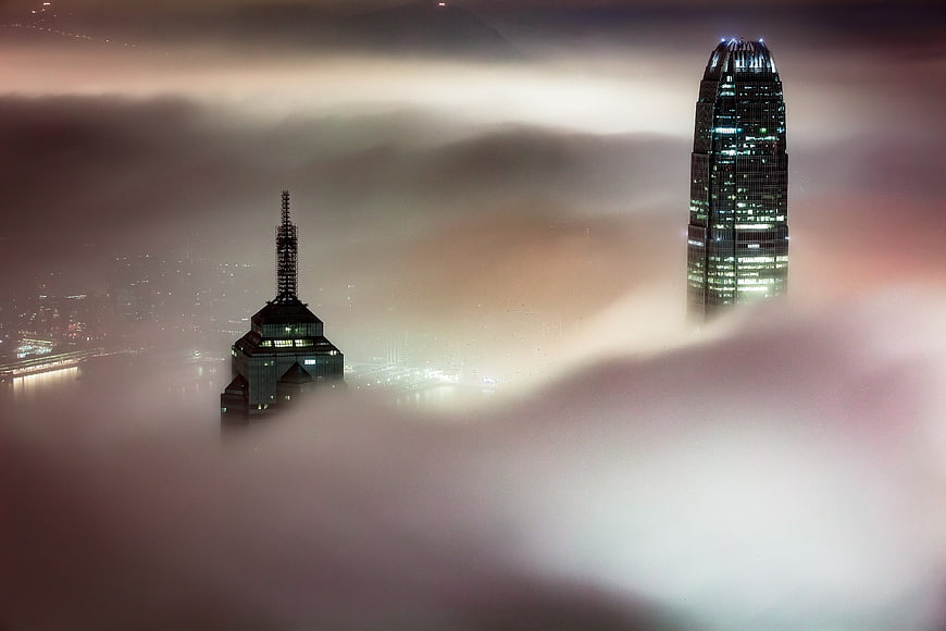 Skyscrapers emerging from thick fog at night in city