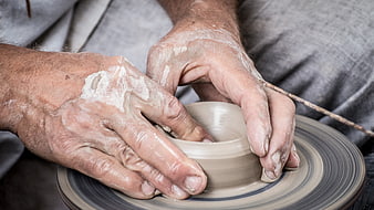 Close-up of potter's hands shaping clay on a spinning wheel