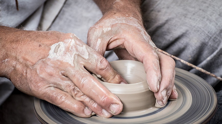 Close-up of potter's hands shaping clay on a spinning wheel