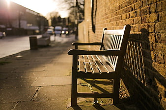 Empty Wooden Bench Against Brick Wall in Golden Hour Sunlight
