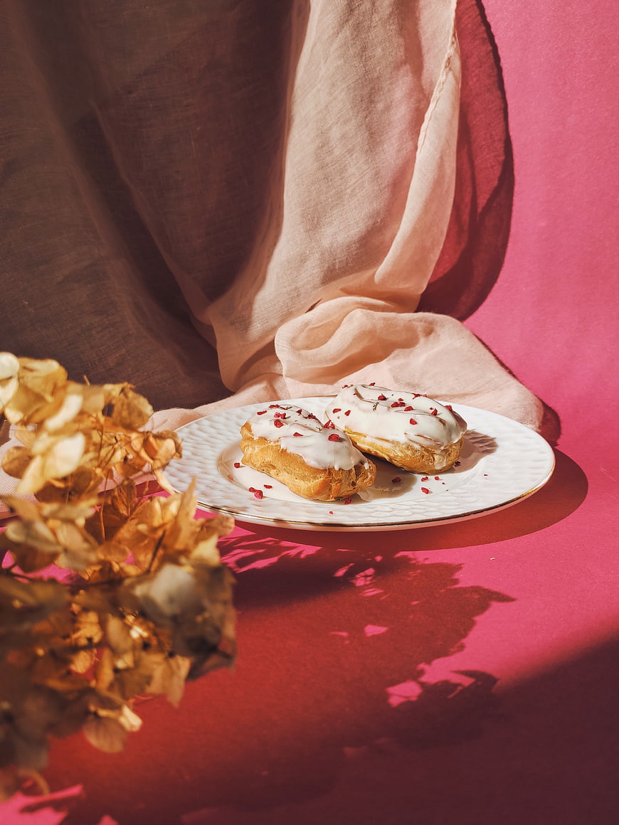 Gourmet eclairs with white glaze on pink background