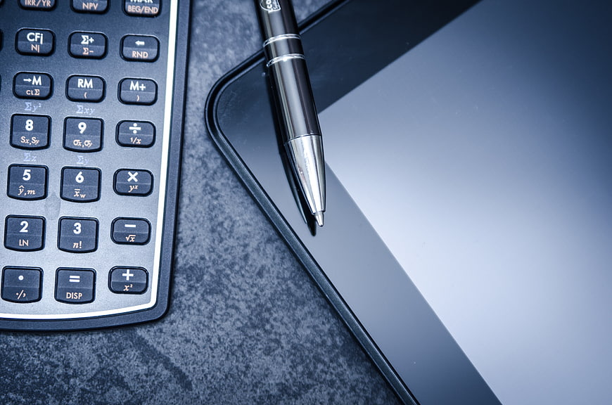 Scientific Calculator, Pen, And Tablet On Dark Desk