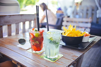 Refreshing cocktails and chips on a wooden table at a beach bar