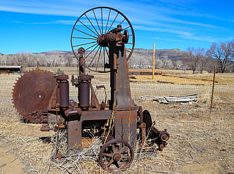 Rusty vintage farm machinery in dry field with blue sky