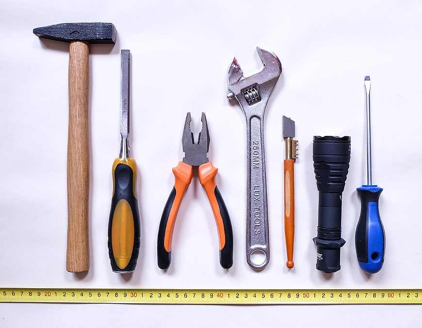 Assorted Hand Tools and Flashlight Arranged on White Background