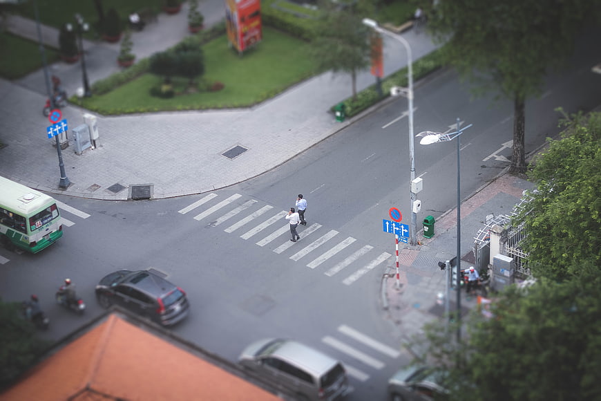 Tilt-shift miniature effect of city street with pedestrians crossing