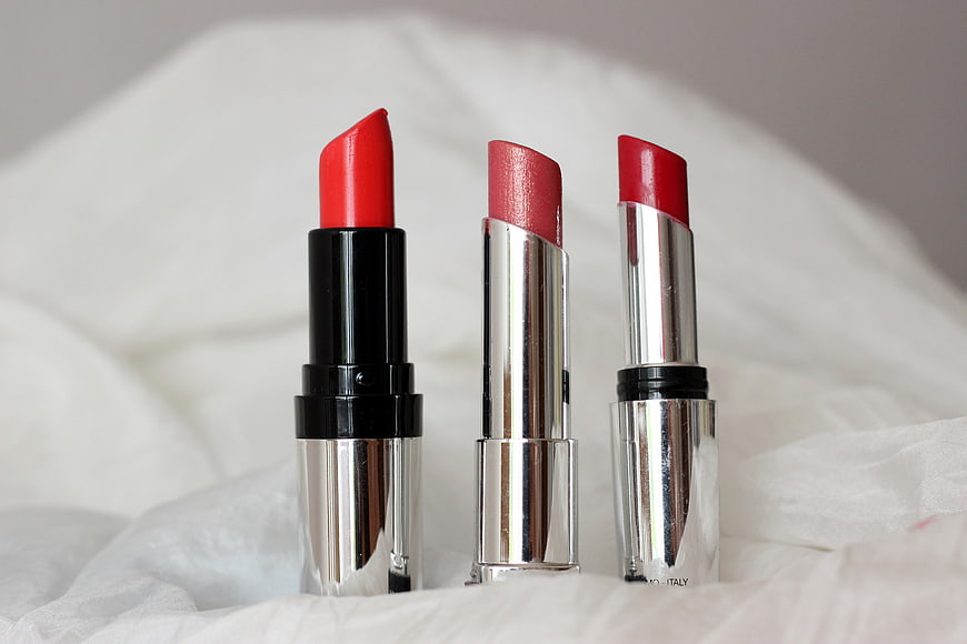 Three Red Lipsticks on White Fabric Background