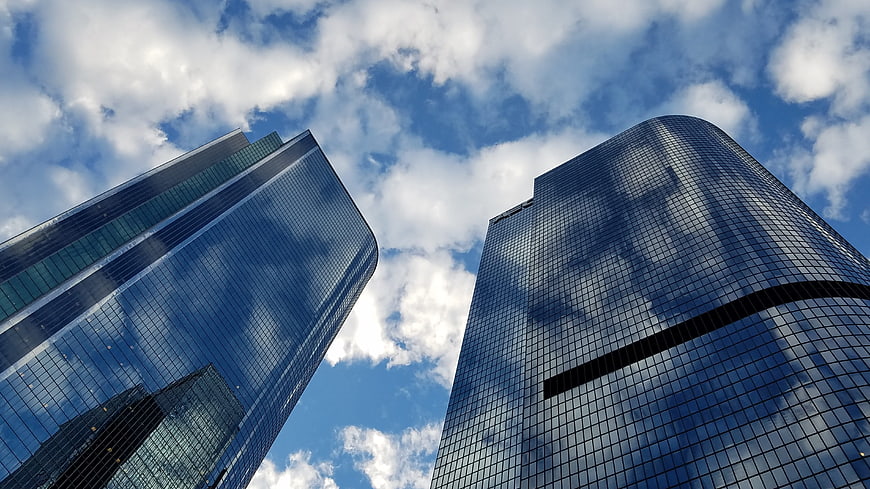 Low angle view of modern glass skyscrapers reflecting clouds