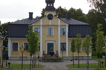 Yellow historic manor house with clock tower and garden