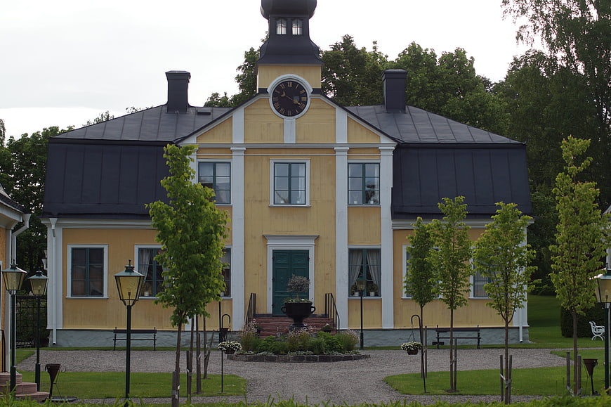 Yellow historic manor house with clock tower and garden