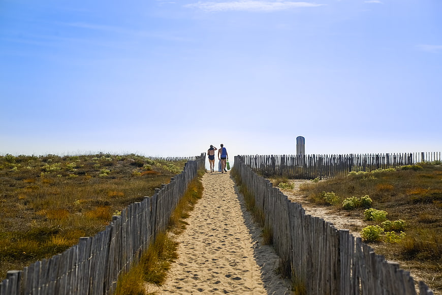 Couple Walking on Sandy Beach Path with Wooden Fences