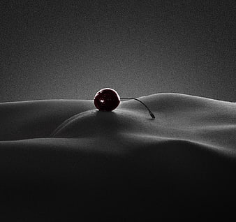 Single Cherry Resting On Draped Fabric In Dramatic Low-Key Lighting