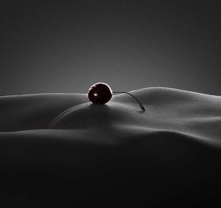 Single Cherry Resting On Draped Fabric In Dramatic Low-Key Lighting