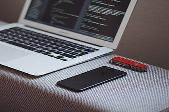 Laptop with Code, Smartphone, and Swiss Army Knife on Desk