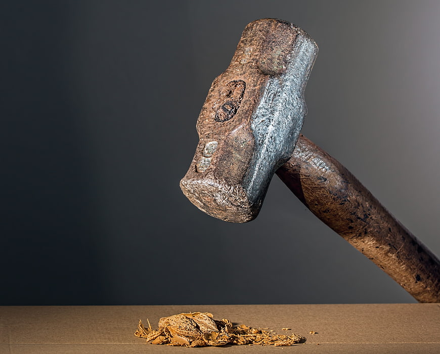 Rusty Sledgehammer Crushing Walnut on Wooden Surface