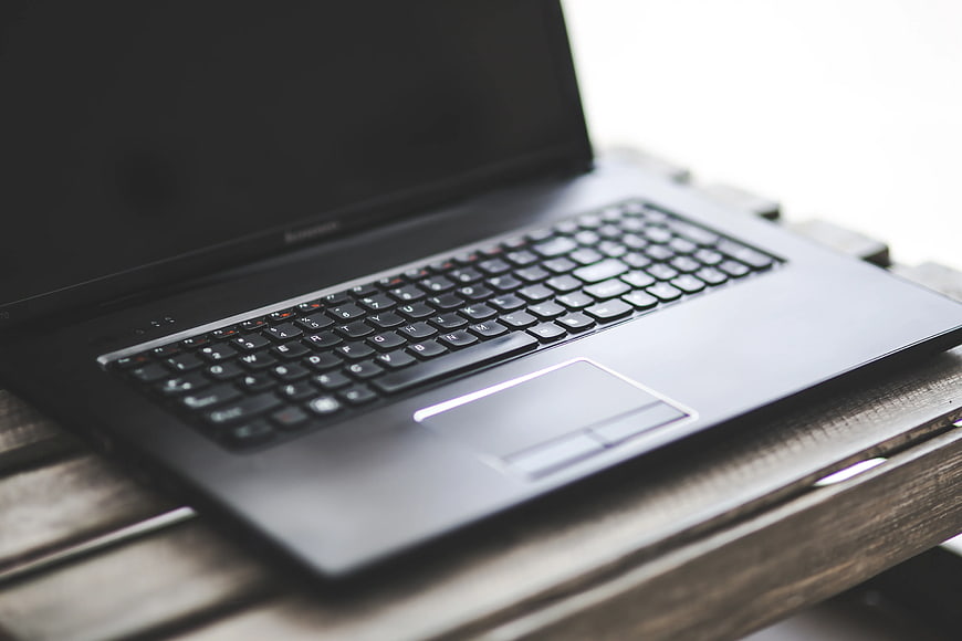 Black laptop on wooden table with shallow depth of field