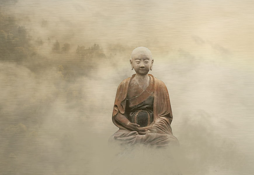Meditating Buddha statue in misty mountain landscape