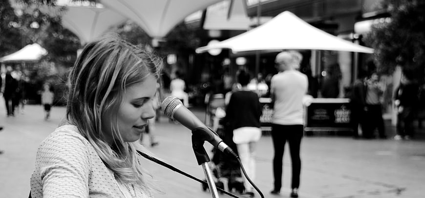 Woman singing into microphone at outdoor street performance