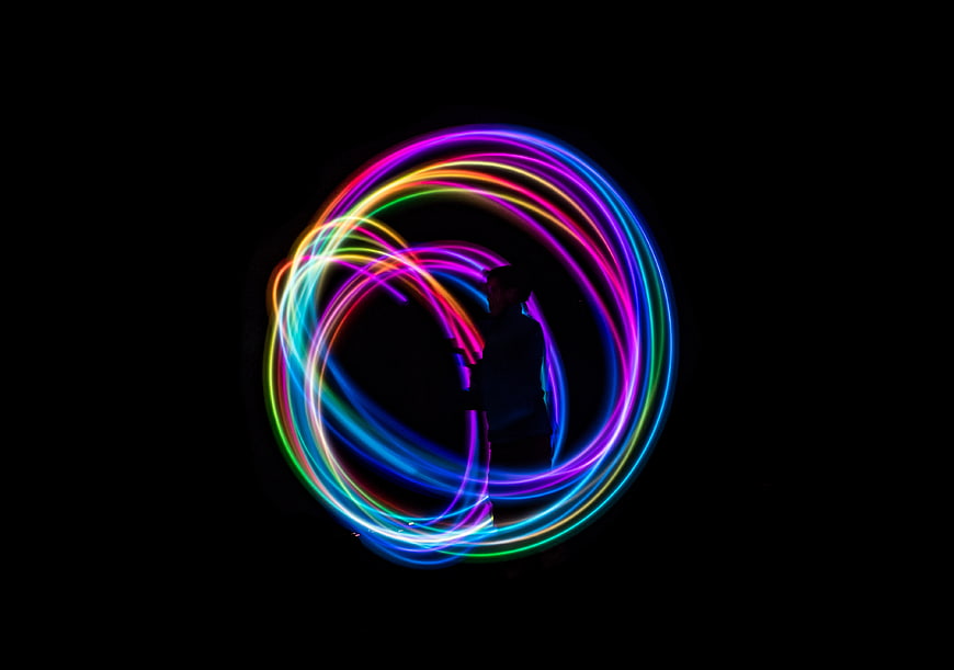 Silhouette of person creating colorful light painting circles in the dark