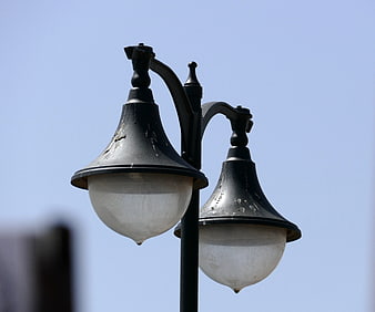 Vintage black double street lamp against blue sky