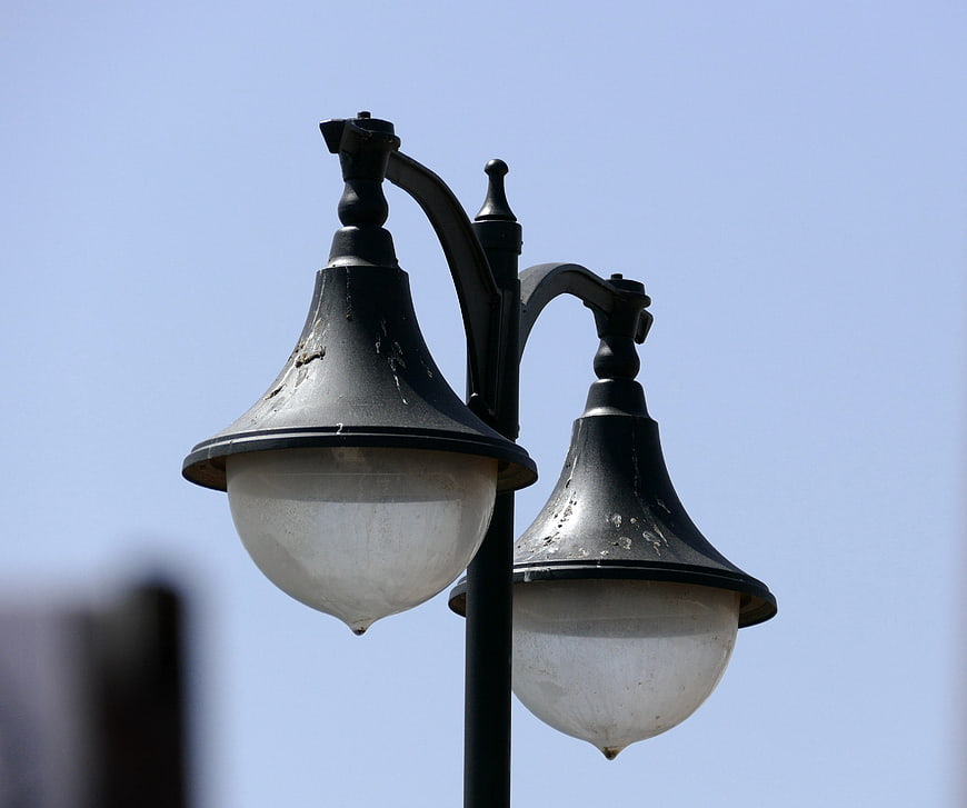 Vintage black double street lamp against blue sky