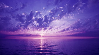 Dramatic Purple Sunset Over Calm Ocean with Clouds